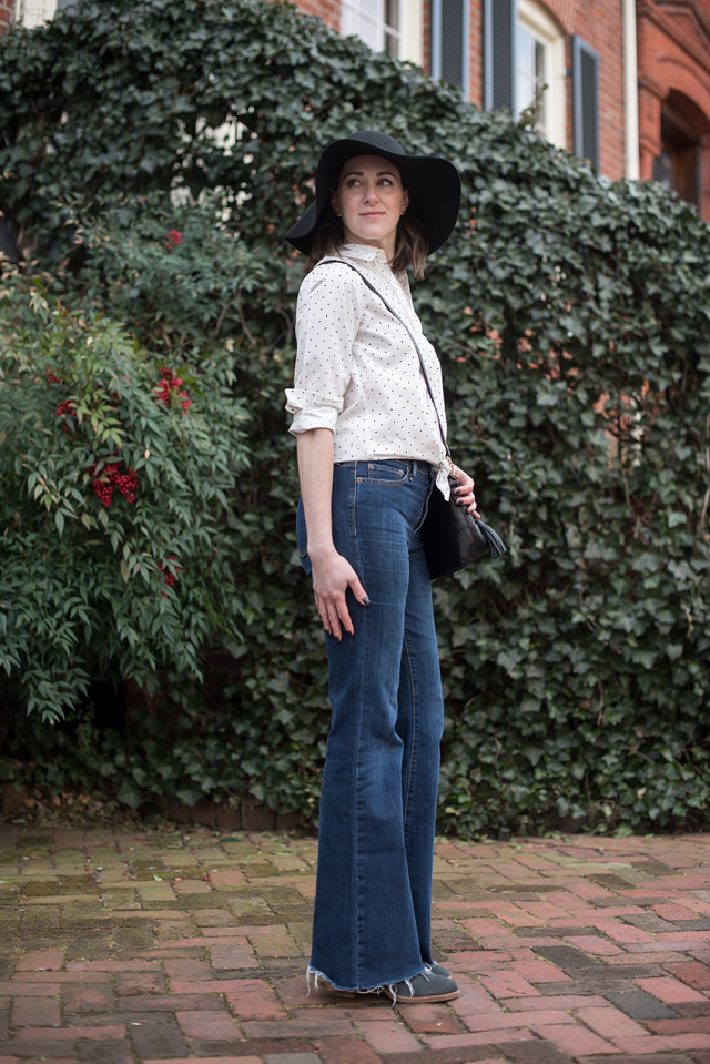 Dark flare jeans, a black and white polka dot shirt, and a floppy festival hat