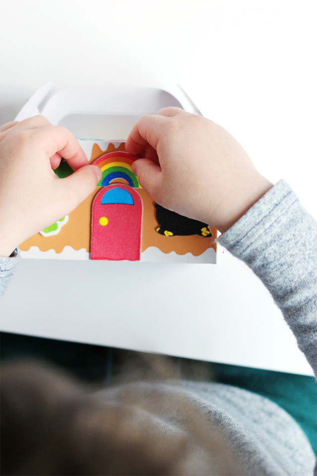 Making a St. Patrick's Day kids' craft using a Christmas gingerbread house and stickers on A Girl Named PJ